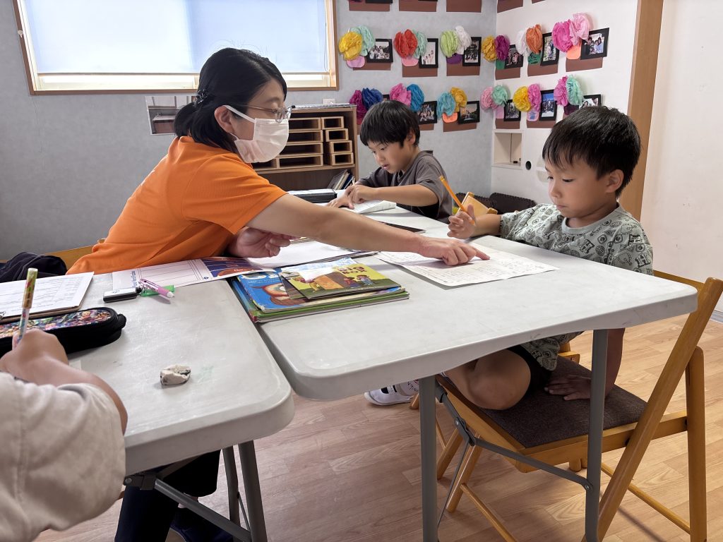 英語学童の宿題サポートを受ける小学生と講師の様子